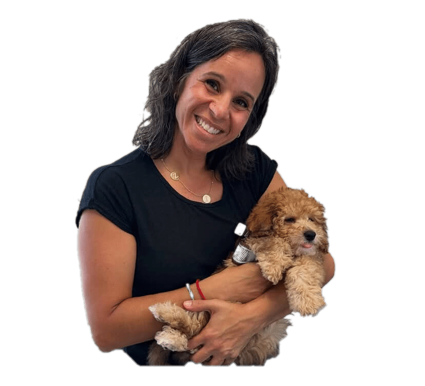 A woman with shoulder-length dark hair, wearing a black shirt, smiles while holding a small brown and white puppy.